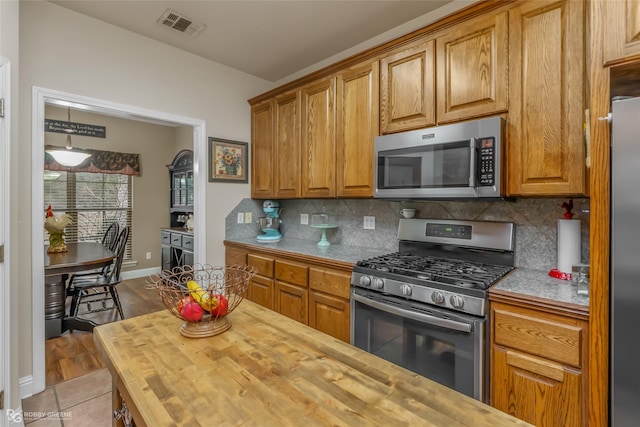 kitchen featuring appliances with stainless steel finishes, butcher block counters, and backsplash