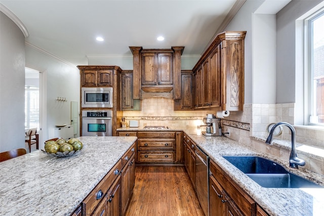 kitchen featuring sink, crown molding, dark hardwood / wood-style floors, stainless steel appliances, and light stone countertops