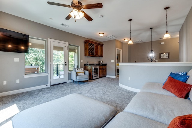 living room featuring ceiling fan, bar, beverage cooler, and carpet floors