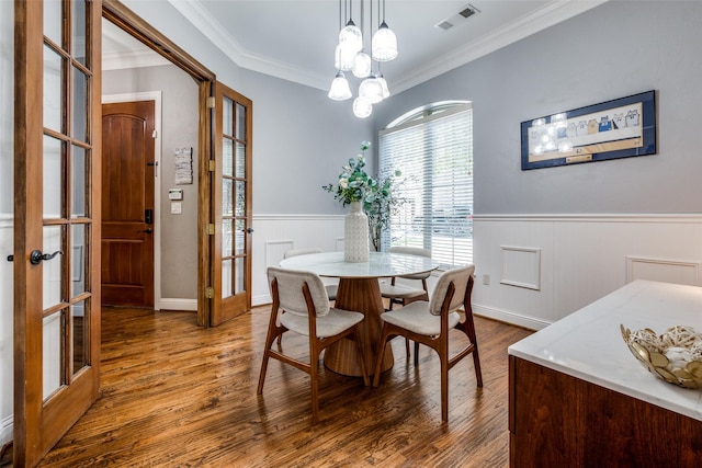 dining area featuring french doors, crown molding, an inviting chandelier, and hardwood / wood-style floors