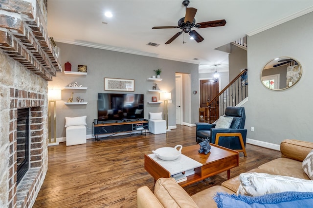 living room with hardwood / wood-style flooring, crown molding, ceiling fan, and a fireplace