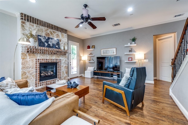 living room with crown molding, a large fireplace, ceiling fan, and hardwood / wood-style flooring