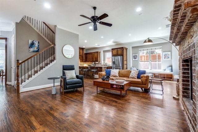 living room featuring sink, a brick fireplace, ornamental molding, dark hardwood / wood-style flooring, and ceiling fan