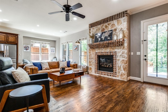 living room featuring crown molding, a stone fireplace, and dark wood-type flooring