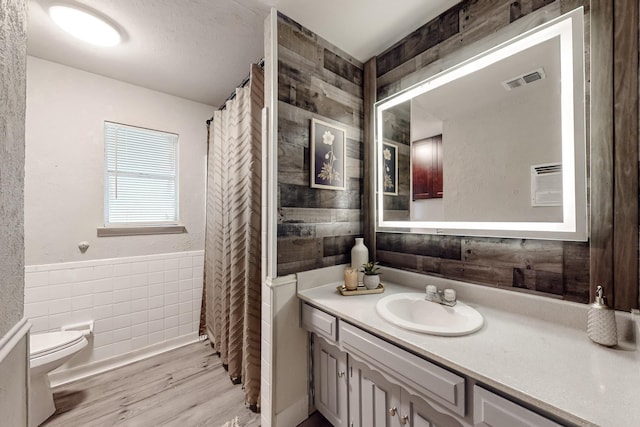 bathroom with hardwood / wood-style flooring, vanity, tile walls, and toilet