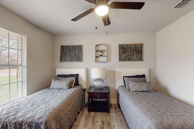 bedroom featuring ceiling fan, light hardwood / wood-style floors, and multiple windows