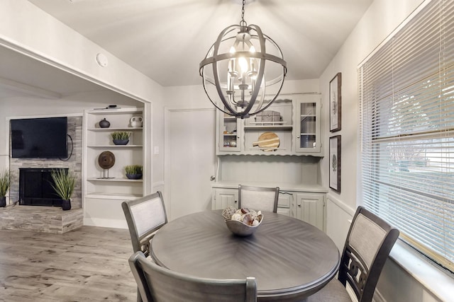 dining space featuring a large fireplace, a chandelier, and light wood-type flooring