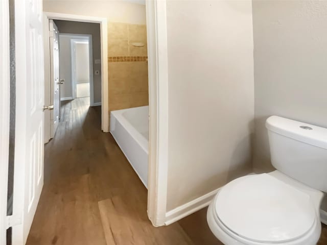 bathroom featuring hardwood / wood-style flooring, toilet, and a tub