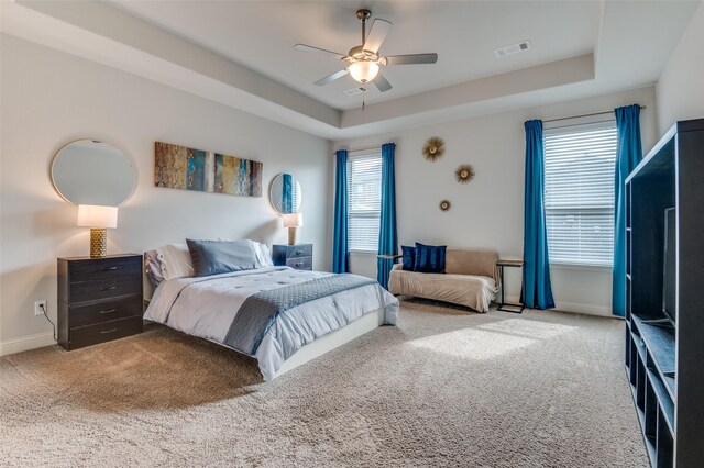 bedroom with carpet floors, a raised ceiling, and ceiling fan