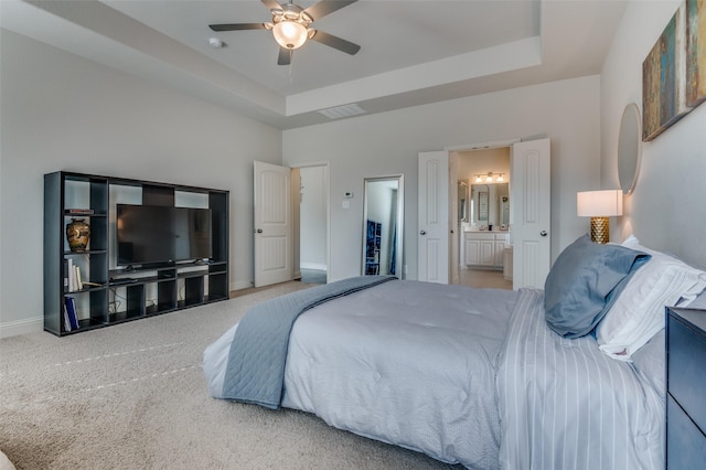 bedroom featuring ensuite bathroom, a raised ceiling, ceiling fan, and carpet flooring