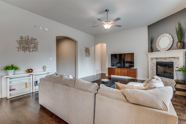 living room featuring ceiling fan, a fireplace, and dark hardwood / wood-style flooring