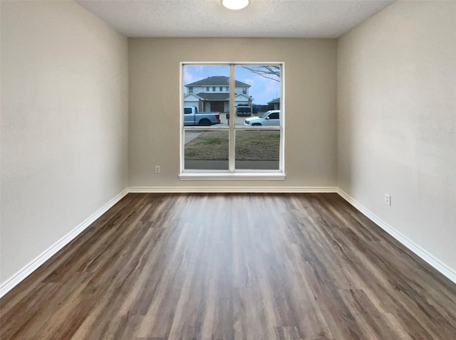 spare room featuring dark wood-type flooring and a textured ceiling