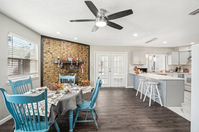 dining area with french doors, a healthy amount of sunlight, dark hardwood / wood-style flooring, and a textured ceiling