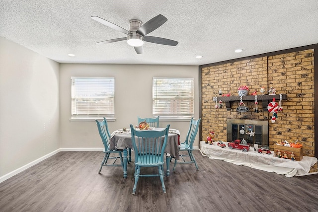 dining area featuring hardwood / wood-style flooring, a healthy amount of sunlight, a brick fireplace, and a textured ceiling