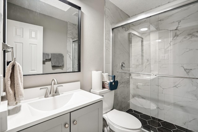 bathroom featuring vanity, a shower with shower door, and toilet