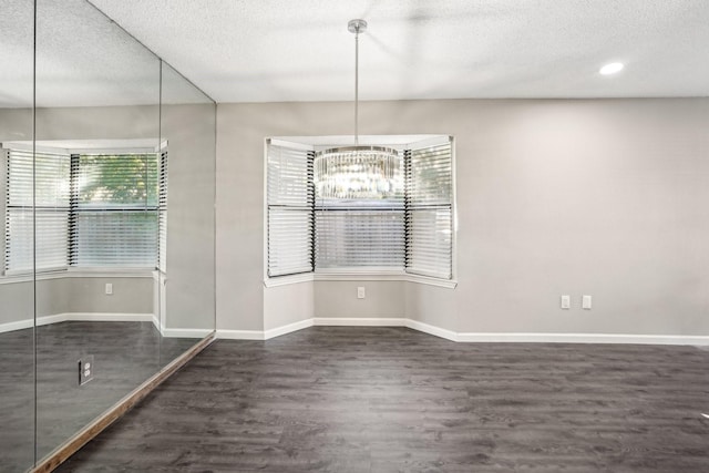 unfurnished dining area with dark wood-type flooring, a chandelier, and a textured ceiling