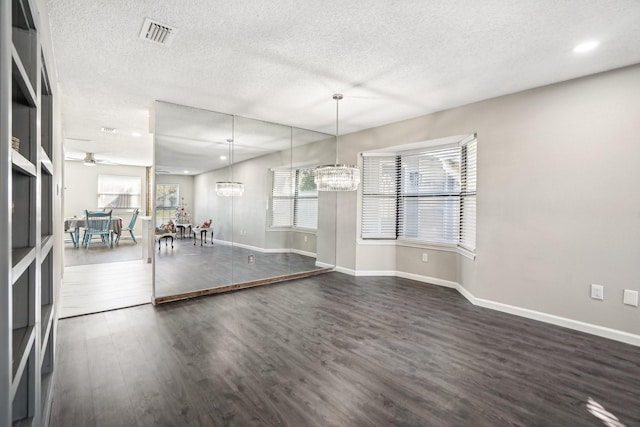 interior space with ceiling fan with notable chandelier, dark hardwood / wood-style floors, and a textured ceiling