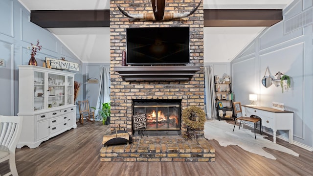 living room with dark wood-type flooring, vaulted ceiling with beams, and a fireplace