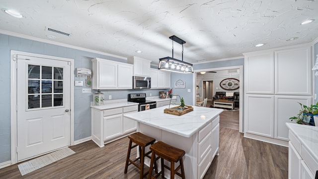 kitchen featuring pendant lighting, stainless steel appliances, white cabinets, and a kitchen island