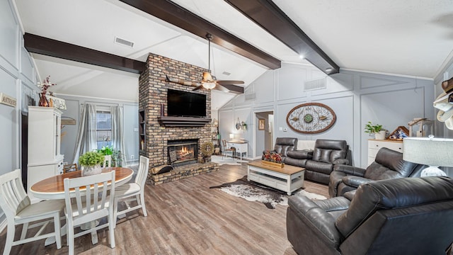 living room with light hardwood / wood-style flooring, vaulted ceiling with beams, a fireplace, and ceiling fan