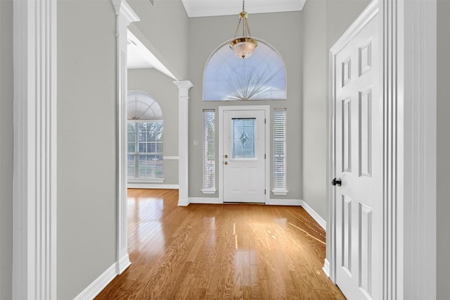 foyer entrance featuring decorative columns and light hardwood / wood-style floors