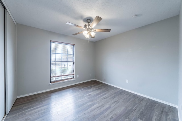 spare room with dark wood-type flooring, a textured ceiling, and ceiling fan