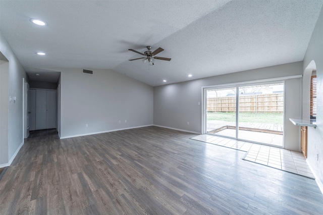 unfurnished living room featuring vaulted ceiling, dark wood-type flooring, ceiling fan, and a textured ceiling