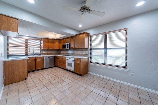 kitchen featuring sink, ceiling fan, appliances with stainless steel finishes, tasteful backsplash, and a textured ceiling