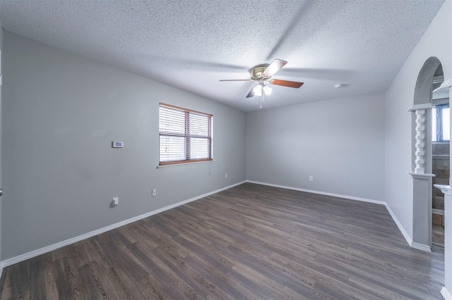 unfurnished room featuring ceiling fan, a healthy amount of sunlight, a textured ceiling, and dark hardwood / wood-style flooring