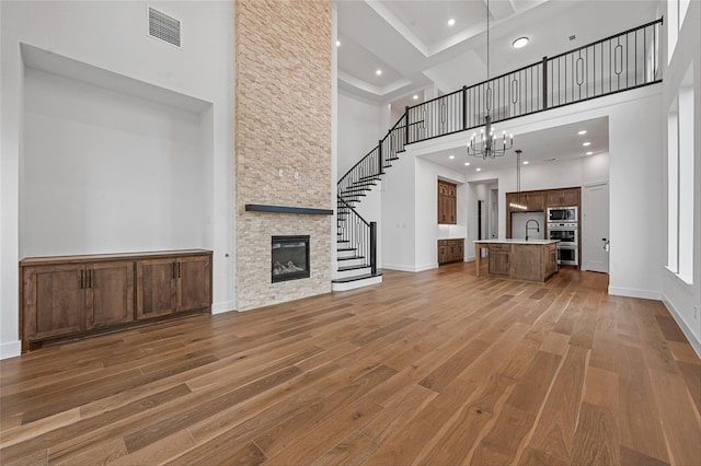 unfurnished living room with a notable chandelier, sink, wood-type flooring, and a fireplace