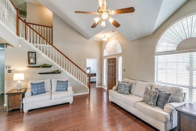 living room with high vaulted ceiling, wood finished floors, ceiling fan, and stairs