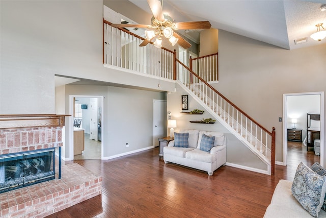 living area featuring baseboards, a ceiling fan, stairway, wood finished floors, and a brick fireplace