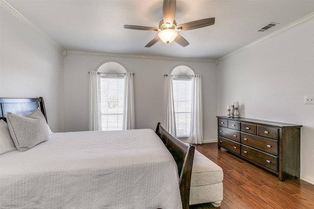 bedroom with wood finished floors, a ceiling fan, baseboards, visible vents, and crown molding