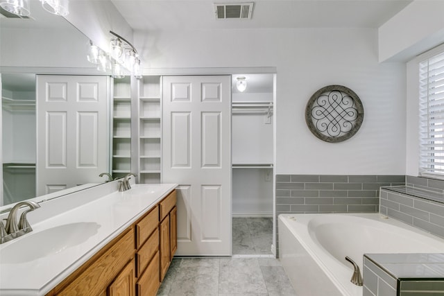 bathroom featuring a walk in closet, visible vents, a sink, and a bath