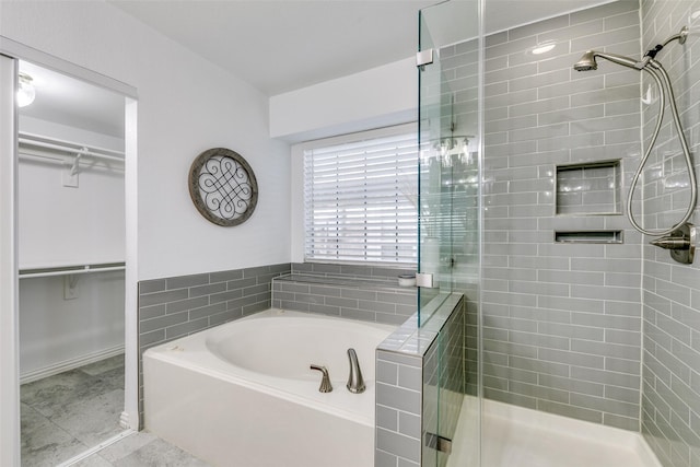 full bath featuring a stall shower, tile patterned flooring, a walk in closet, and a bath