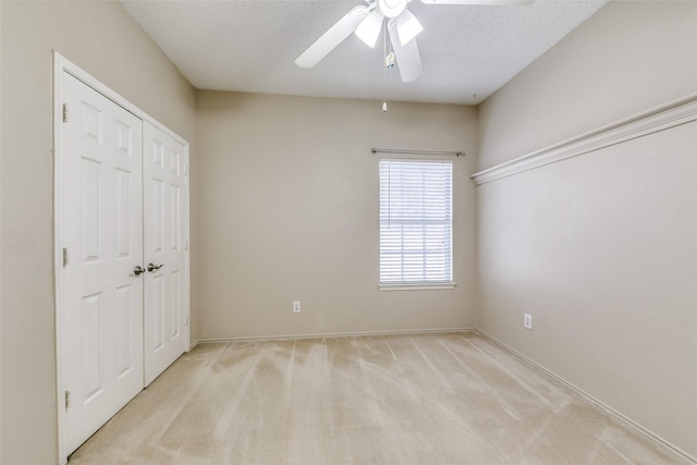 unfurnished bedroom with ceiling fan, a textured ceiling, a closet, and light colored carpet