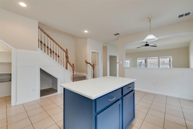 kitchen with blue cabinets, decorative light fixtures, a kitchen island, and light tile patterned floors