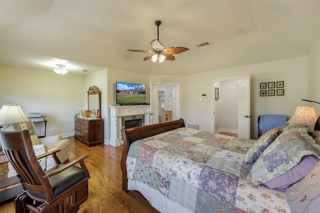 bedroom featuring ceiling fan, light hardwood / wood-style floors, and a tile fireplace