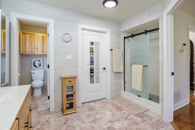 bathroom featuring vanity, toilet, a shower with door, and tile walls