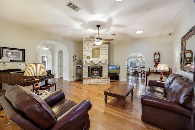 living room with ceiling fan, a fireplace, and light hardwood / wood-style flooring