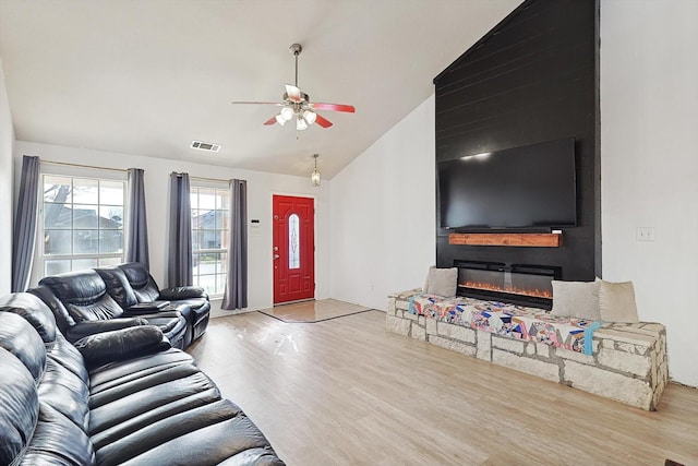 living room featuring ceiling fan, lofted ceiling, and light hardwood / wood-style floors