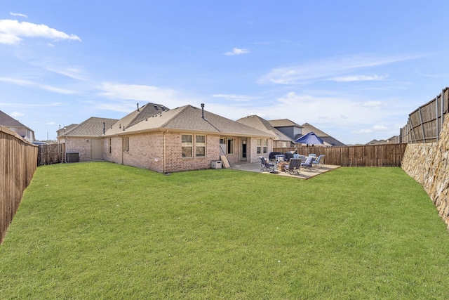 back of property with a patio, brick siding, a lawn, and a fenced backyard