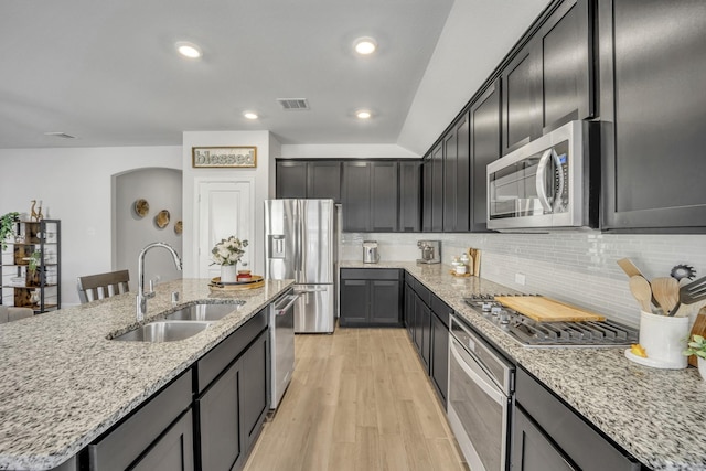 kitchen featuring light wood finished floors, visible vents, backsplash, appliances with stainless steel finishes, and a sink