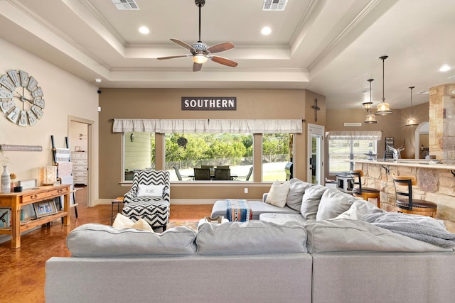 living room with crown molding, ceiling fan, and a tray ceiling