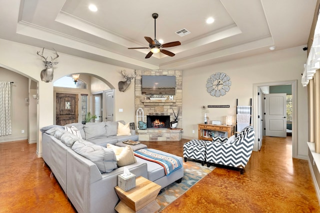 living room featuring ornamental molding, ceiling fan, a fireplace, and a tray ceiling