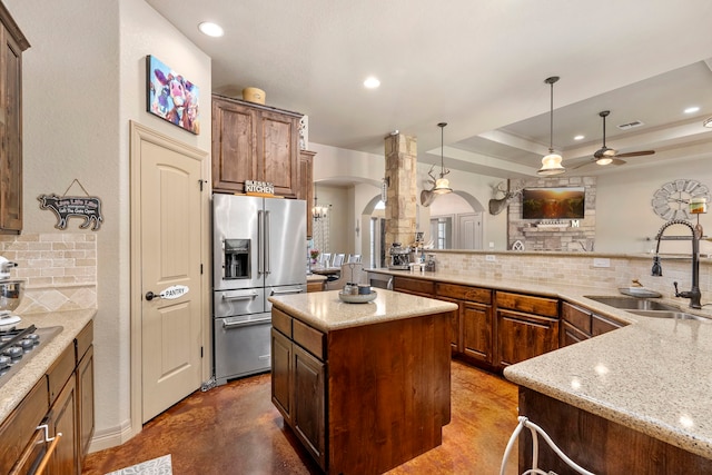 kitchen featuring sink, light stone counters, hanging light fixtures, a kitchen island, and stainless steel appliances