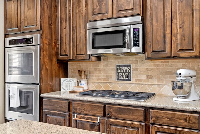 kitchen with stainless steel appliances, light stone countertops, and decorative backsplash