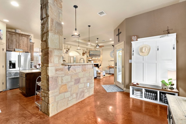 kitchen with hanging light fixtures, stainless steel refrigerator with ice dispenser, a breakfast bar area, and ceiling fan