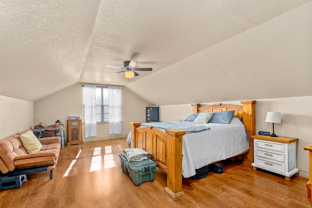 bedroom with lofted ceiling, ceiling fan, light hardwood / wood-style floors, and a textured ceiling