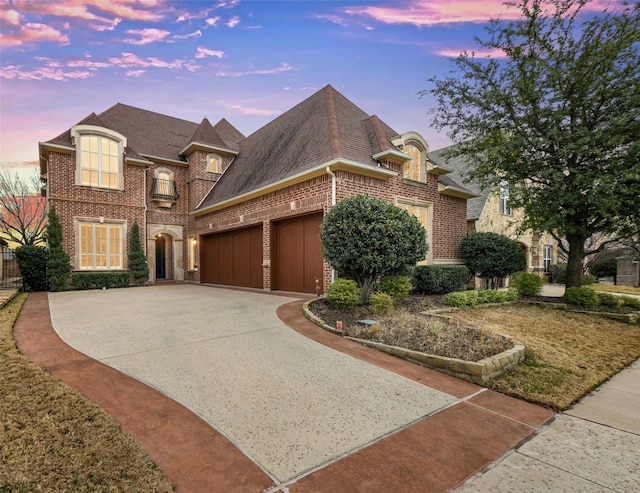 french country style house with a garage, brick siding, and driveway